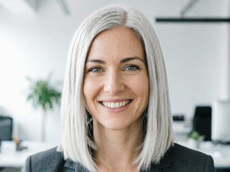 Portrait of the same professional woman with silver-white hair after an effect was applied, against a blurred office background.