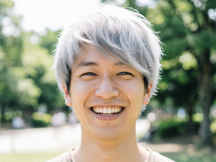 Portrait of the same young man, hairstyle unchanged but colored silver-white after an effect was applied, still maintaining a bright smile.