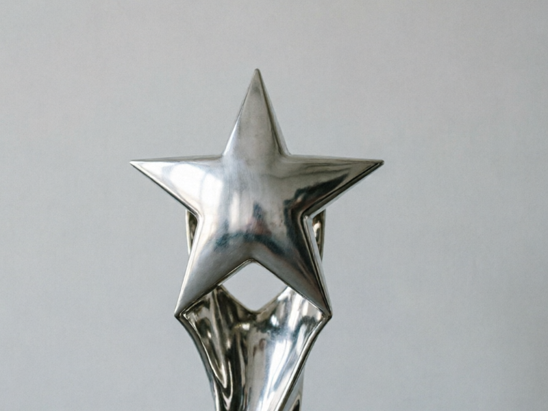 The original low-resolution version of the same trophy. Metallic surfaces show flat, featureless reflections; edges are blurred; the background is plain gray with no atmospheric elements — appearing monotonous and visually flat, representing basic unenhanced material.