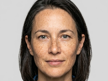 Frontal close-up of the same woman without sunglasses, revealing clear eyes. Her expression is neutral and serious against a solid gray background. The lighting is even and soft, meeting visa photo requirements for facial clarity.