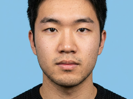 A frontal bust shot of the man with the phone and study background removed. Wearing the same black sweater with a serious, focused gaze against a uniform light blue background, adhering to formal ID photo standards.