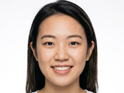 A frontal headshot of the woman with the outdoor background and dynamic pose removed. Her long hair falls over her shoulders, and she offers a bright, toothy smile against a pure white background, presenting a clear and professional ID photo look.