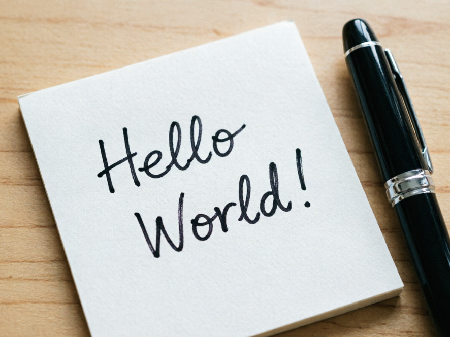A high-contrast image, with the left side showing a clear top-down photo of a desk, with a white sticky note clearly displaying black handwritten English text "Hello World!" on it, next to a dark blue fountain pen with its nib pointing to the right; the right side shows the effect of the same photo after applying a horizontal mirror invert filter
