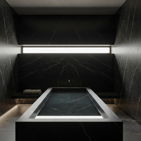 A 1:1 moody bathroom designed with monolithic dark quartzite. A single, long horizontal slit window provides a thin line of daylight. The water in the black stone basin is perfectly still, creating a mirror effect.