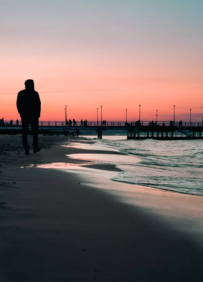 Person walking on a beach at sunset with a moving Watermark text overlay